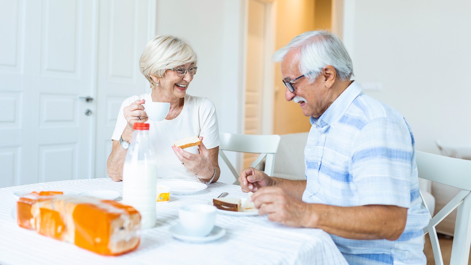 old-senior-laughing-warmly-and-smiling-at-a-sunlit-outdoor-dinner-table-with-family